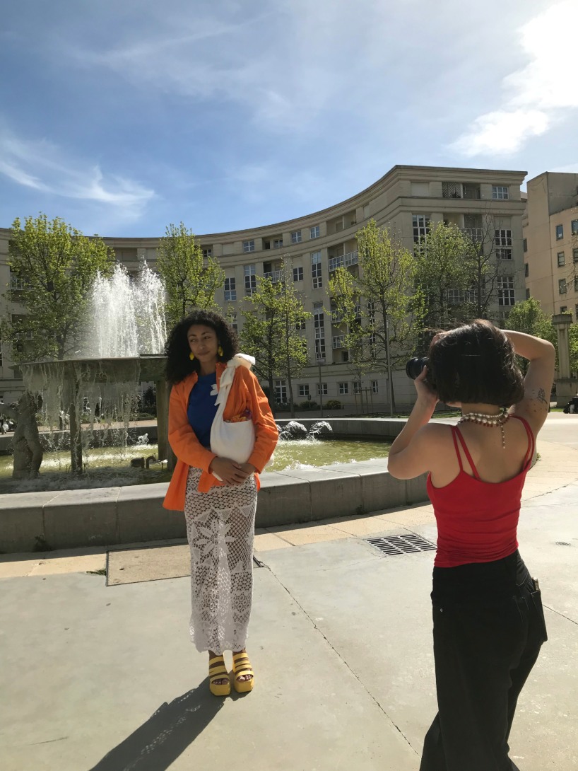Coulisses d’un shooting Maison Janie avec mannequin posant près d’une fontaine, capté par O3il Production.
