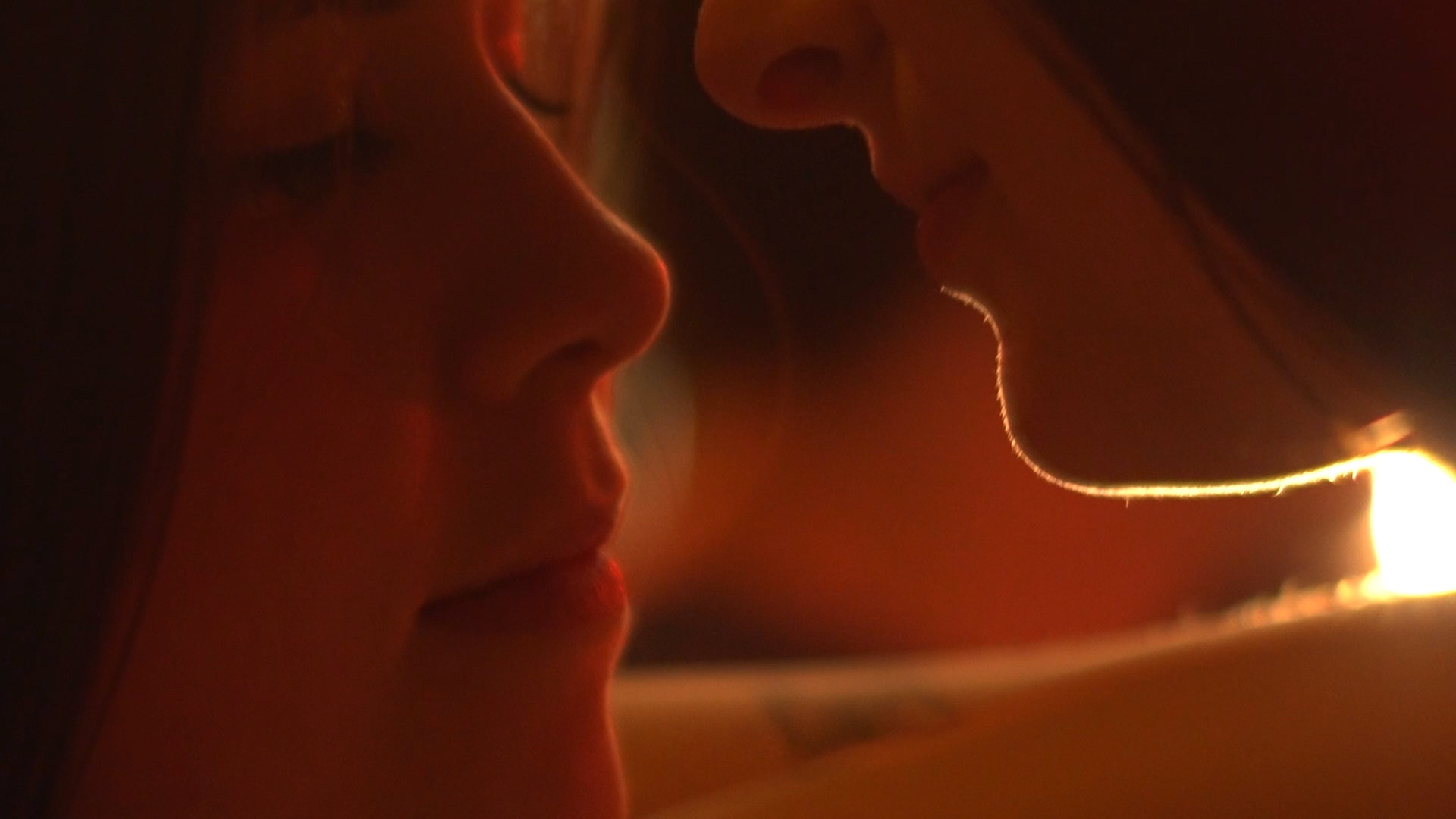 Plan rapproché montrant les visages des deux femmes du clip Limpide se frôlant dans une ambiance feutrée.