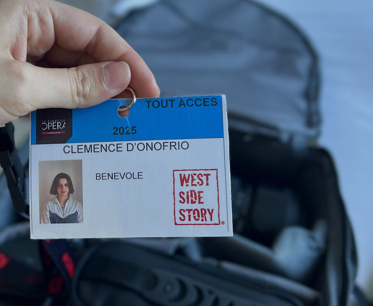 Badge tout accès de Clémence D’Onofrio, bénévole pour la comédie musicale West Side Story à La Fabrique Opéra Grenoble, tenu en main devant du matériel de tournage.