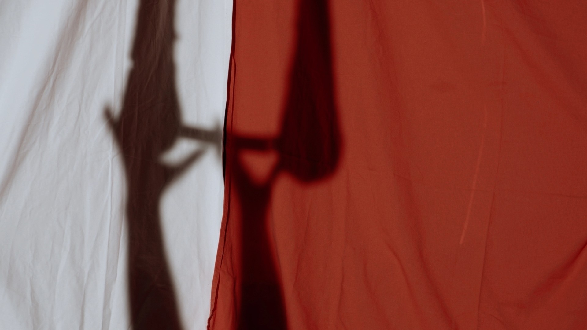 Silhouette d’une trapéziste projetée sur un rideau rouge et blanc dans le projet Icare, une image signée O3il Production.