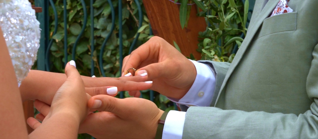 Margo glissant une alliance au doigt de Céline lors de leur cérémonie de mariage, capturée par O3il Production pour un film souvenir plein d’émotion.