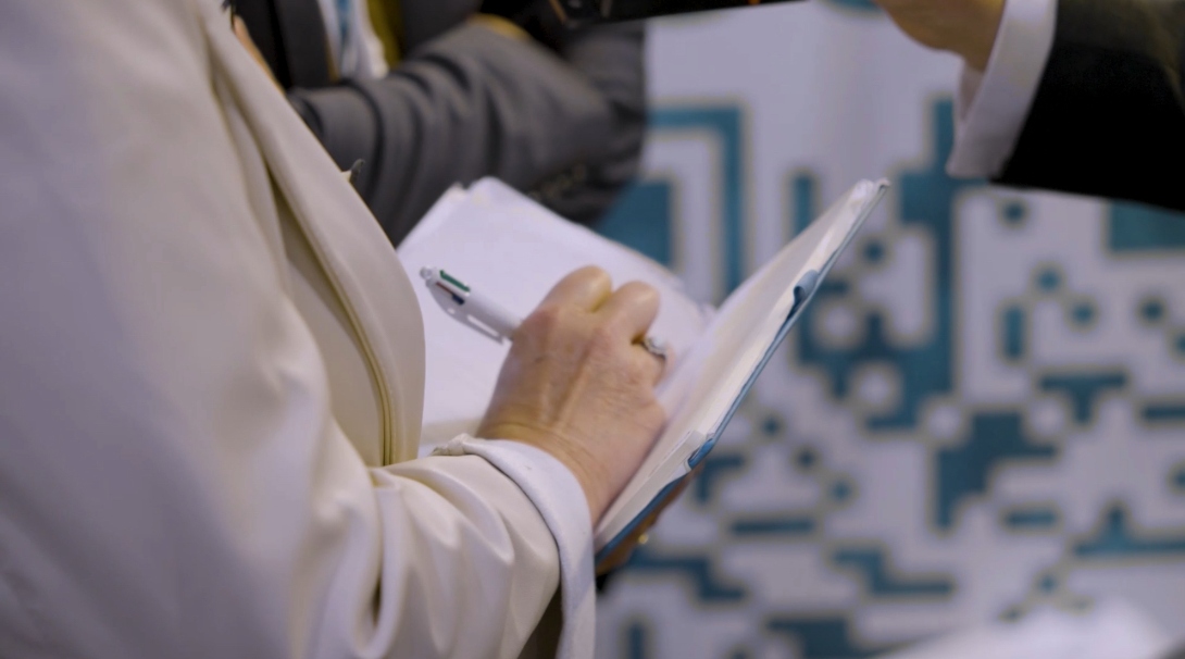Plan serré sur une personne prenant des notes lors d’une rencontre professionnelle au Tech&Fest 2025 avec la participation de ZCE.