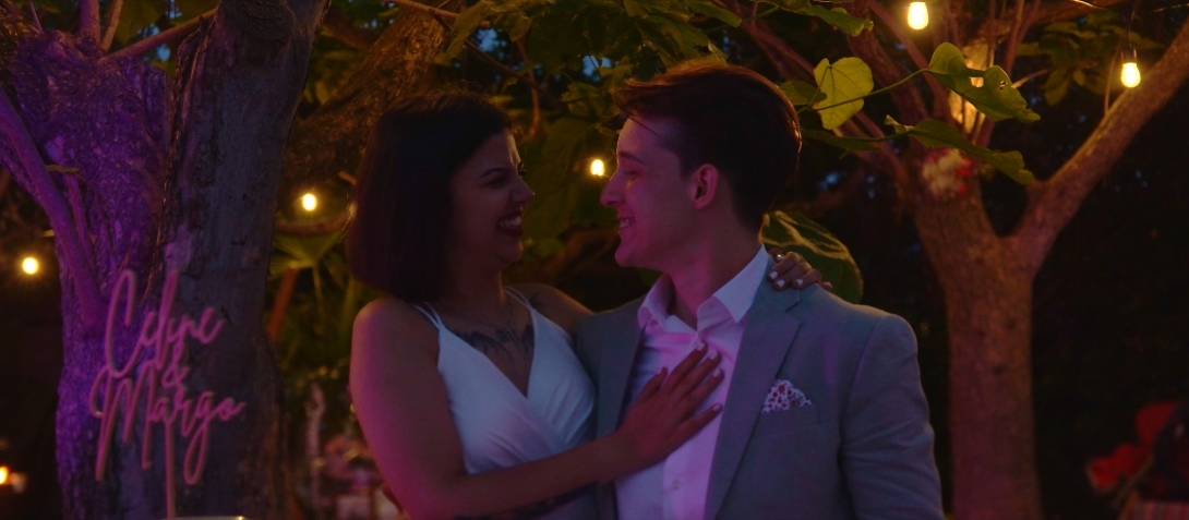Céline et Margo s’enlacent sous des guirlandes lumineuses, partageant un moment complice pendant la soirée de mariage.